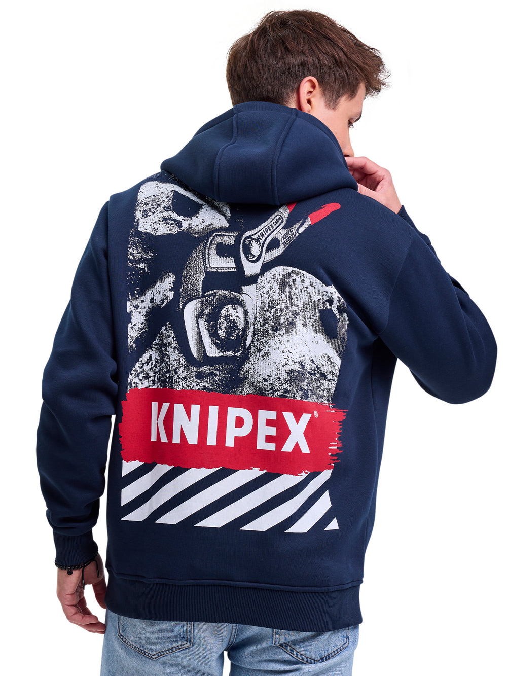 Eine Person trägt einen dunkelblauen Hoodie mit einem auffälligen Design auf der Rückseite. Das Design zeigt Werkzeugmotive, einen roten "Knipex"-Schriftzug und weiße Streifen. Dazu werden hellblaue Jeans kombiniert.